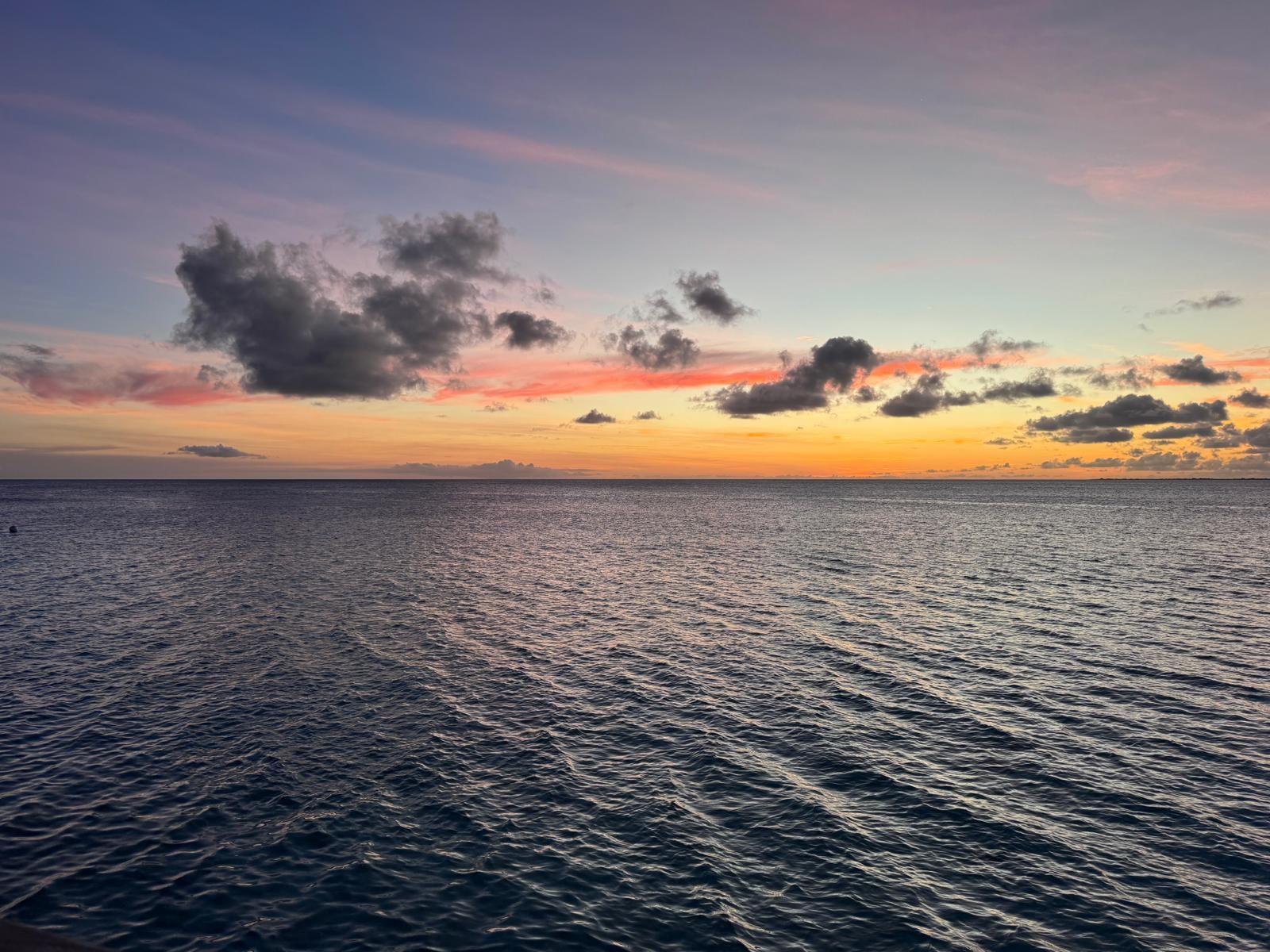 Zonsondergang met wolken boven een kalme zee op Bonaire