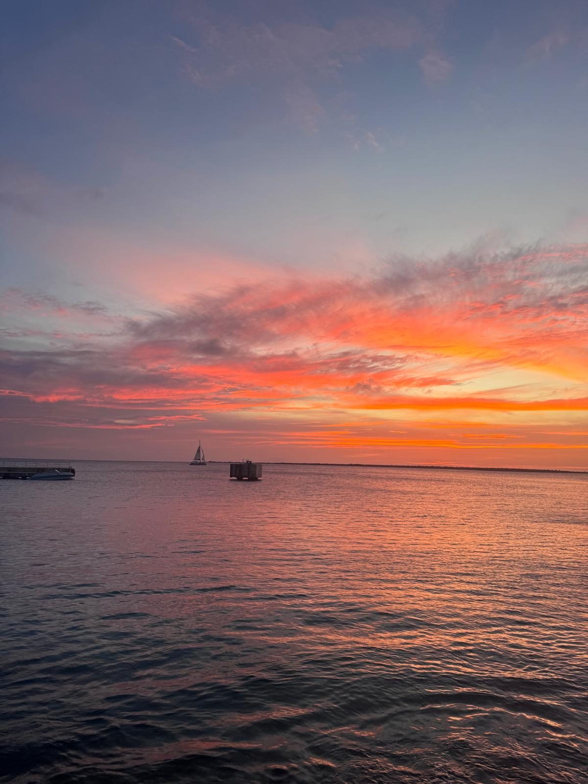 Zeilboot bij een pier tijdens zonsondergang op Bonaire